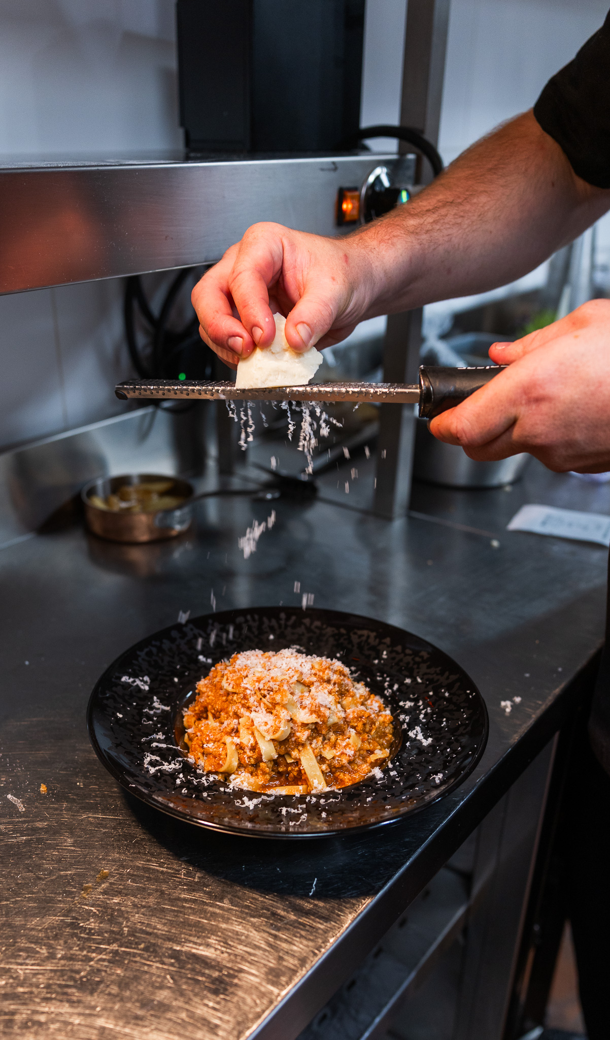 Chef Magari râpe le parmesan sur les pâtes
